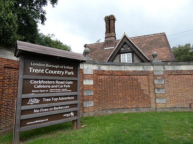 Brick wall winding around Trent Park, with a sign on the exterior