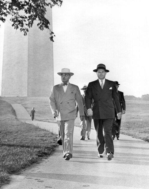 President Truman walking with a secret service entourage.