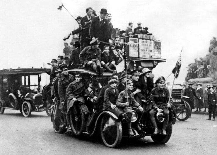 Soldiers and civilians crowded onto a taxi that's driving down a street