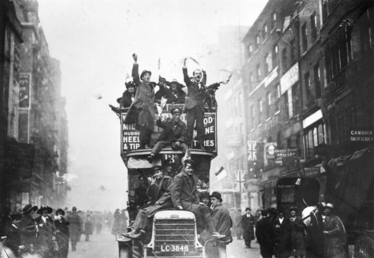 Civilians crowded atop a vehicle driving down a street