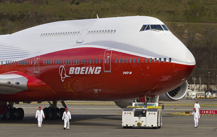 Ground crewmen walking around a Boeing 747-8 that's parked on the tarmac