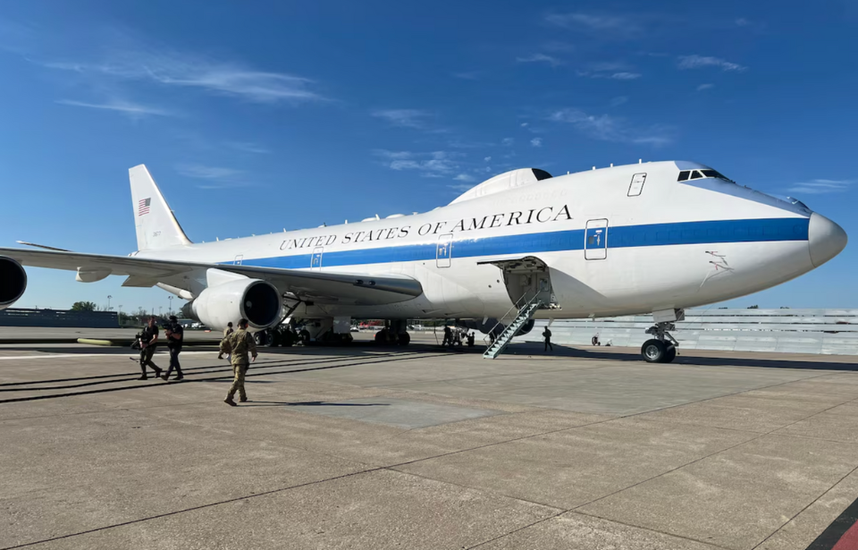 Ground crewmen walking toward a Boeing E-4 that's parked on the tarmac