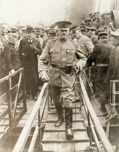 John J. Pershing walking off a ship, while men are gathered behind him