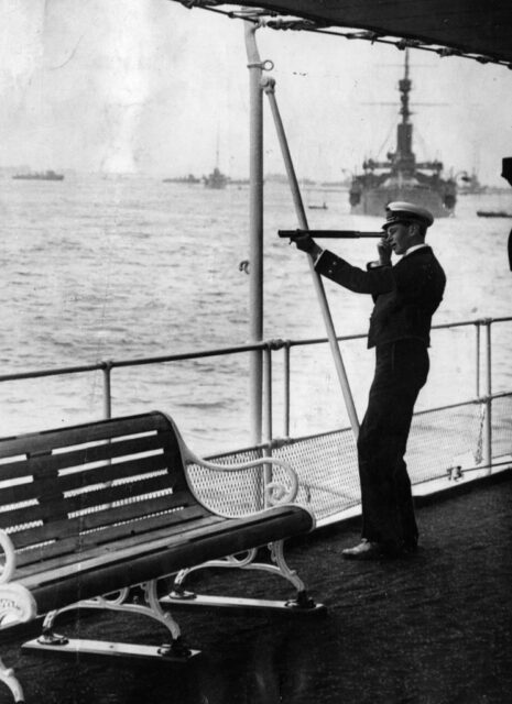 King George VI (then Prince Albert) looking through a periscope on the deck of a ship