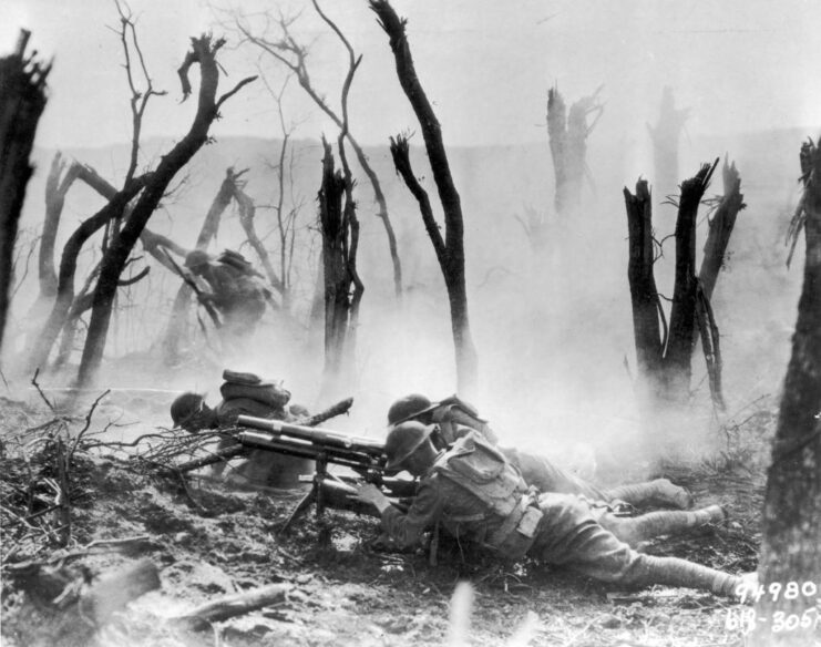 Soldiers with the 23rd Infantry Regiment, 2nd Infantry Division aiming their weapons while lying on the ground of a destroyed forest area