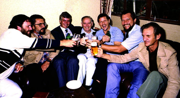 Mike Hoare and members of the "Frothblowers" sitting on a couch, with glasses in their hands