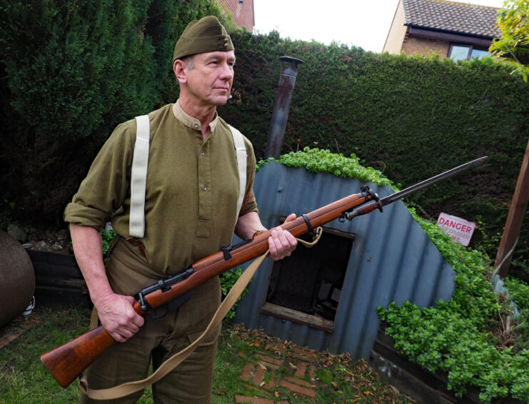 Trad Casey holding a rifle while standing in his back garden