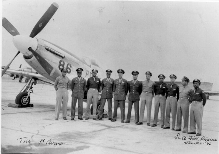 Eleven Tuskegee Airmen standing next to a North American P-51 Mustang