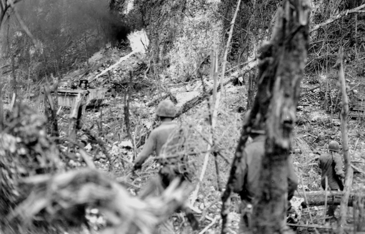 US Marines watching a flamethrower being fired at Japanese fortifications on Peleliu