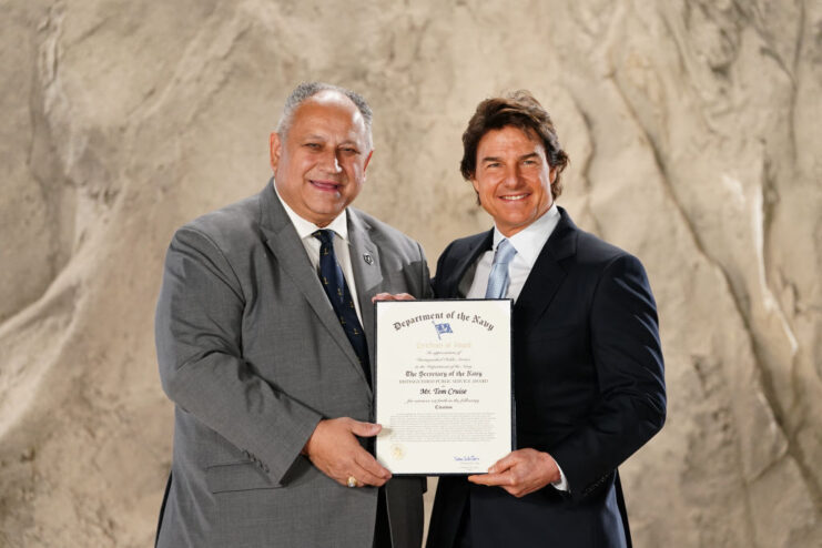 Carlos Del Toro and Tom Cruise holding up a certificate