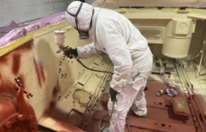 Man spraying paint on a partially-restored M47 Patton